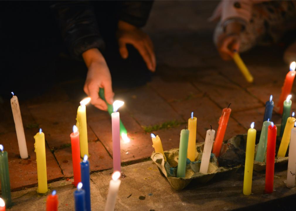 A close up of colorful candles being lit.