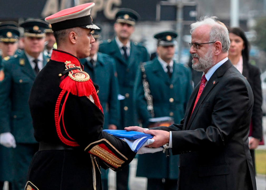 North Macedonia’s Talat Xhaferi hands NATO flag to an army officer during ceremony