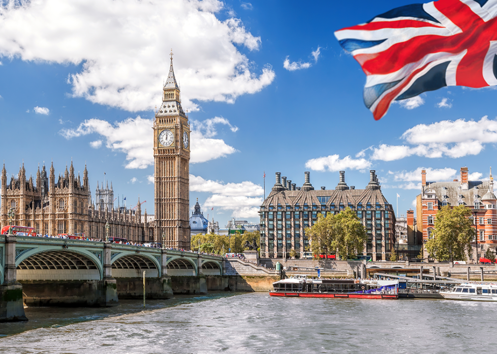 #13. London Big Ben with bridge over Thames and flag of England against blue sky.