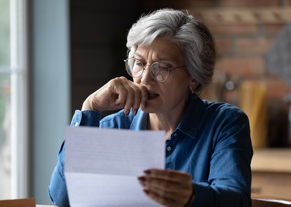 Concerned woman reading letter.
