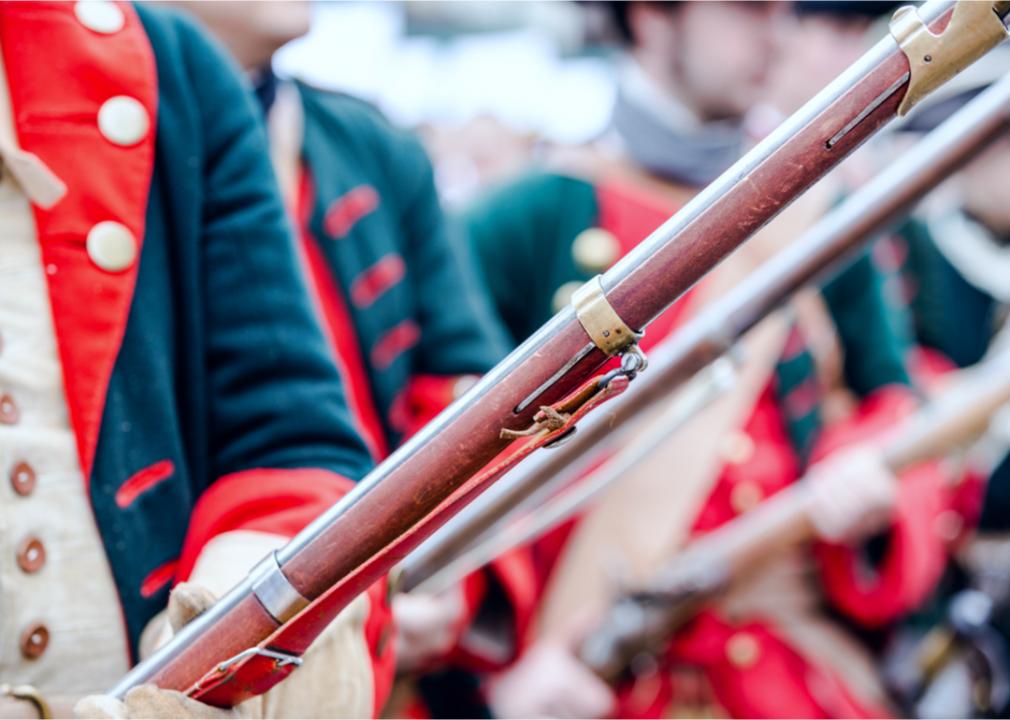 A close up of Revolutionary War uniforms and weapons in what seems to be a reenactment. 