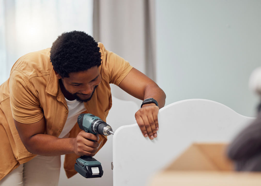 Person assembling furniture, using an electric drill.