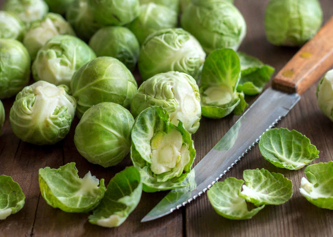 Brussels sprouts with knife on cutting board.