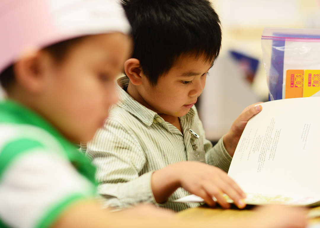 Young Asian student looking at book in classroom.