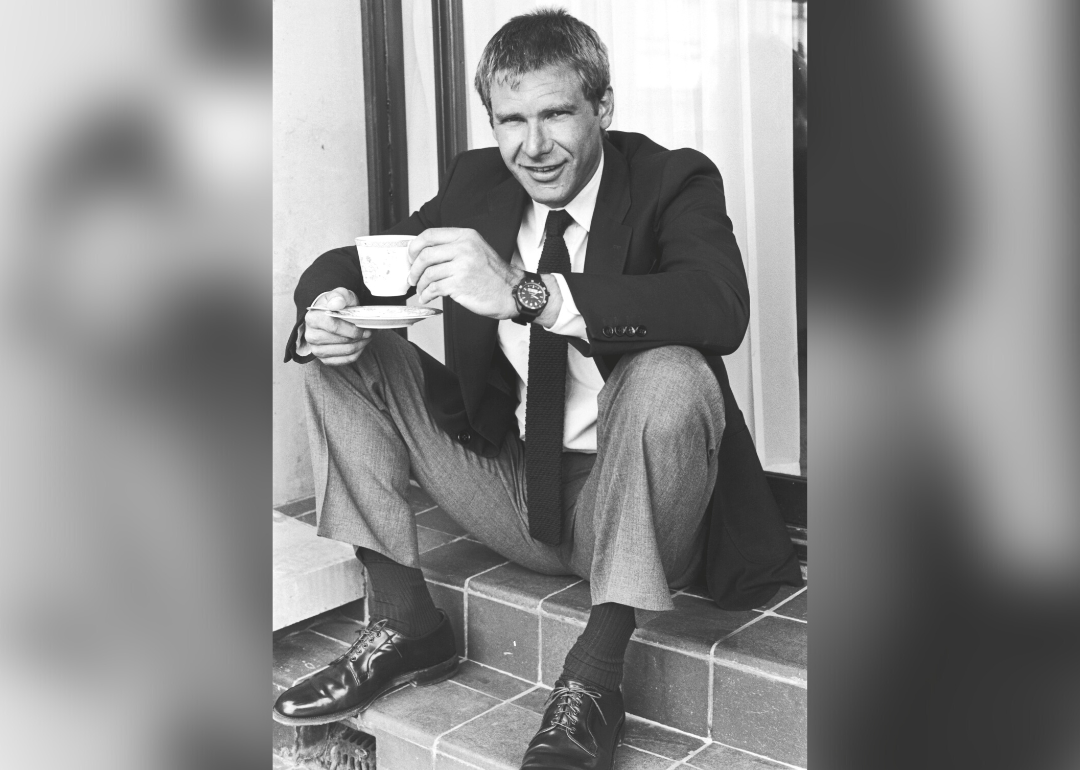 Harrison Ford sits on steps with teacup