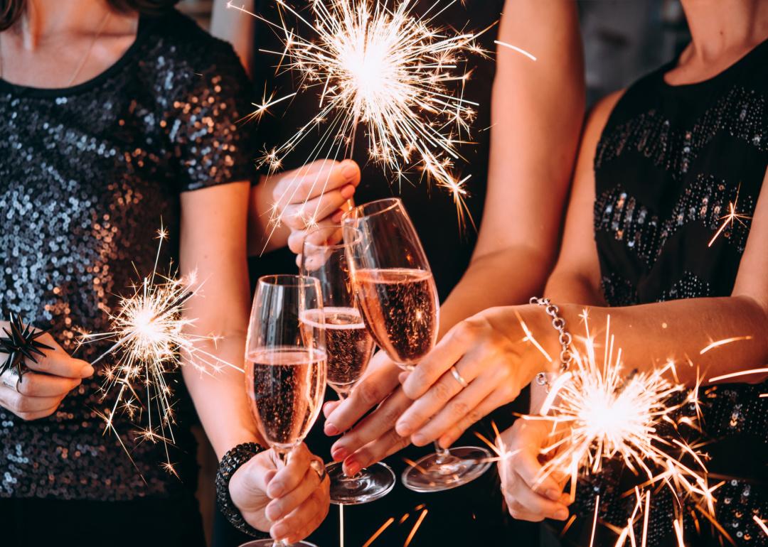 Cropped view of friends toasting with Champagne and holding sparklers.