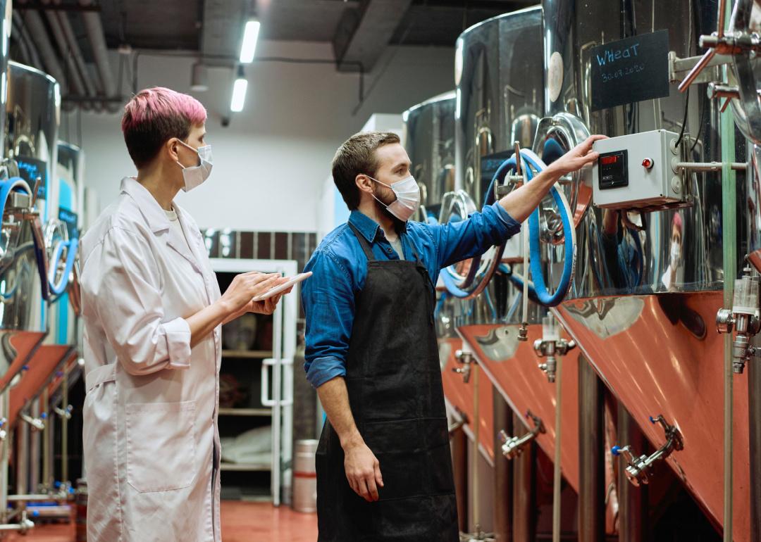 Two brewers review production equipment.