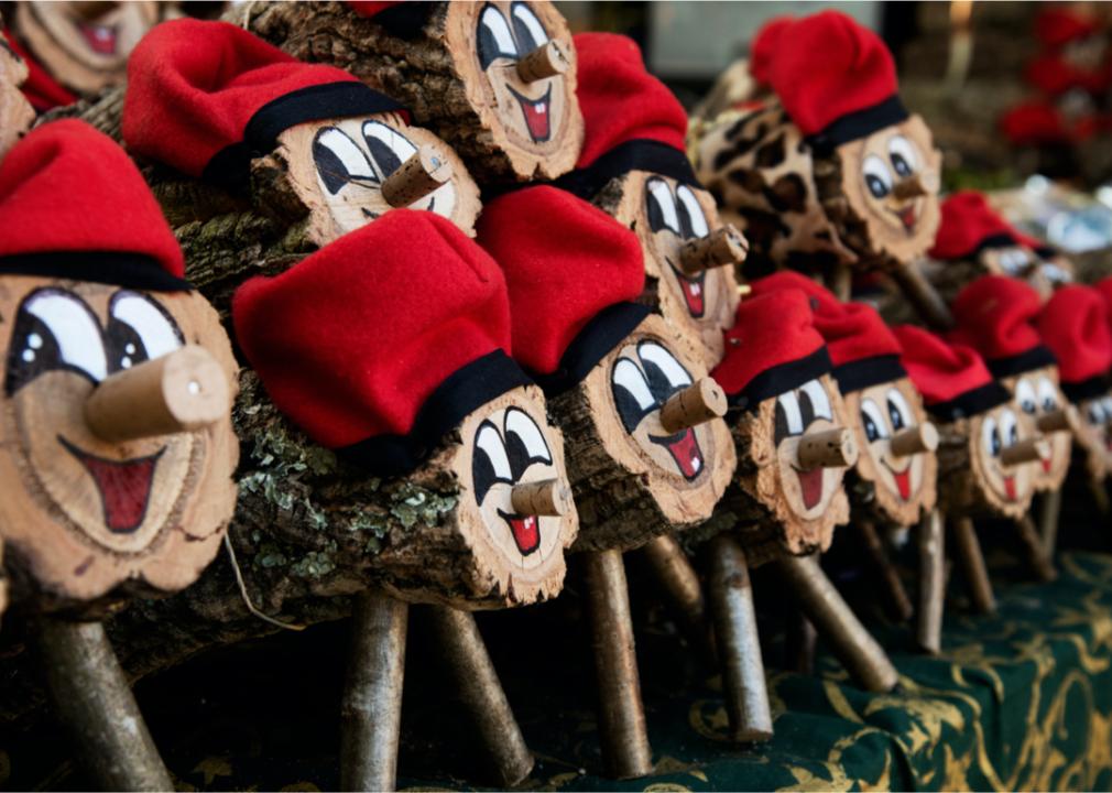 A pile of logs with faces and red hats.