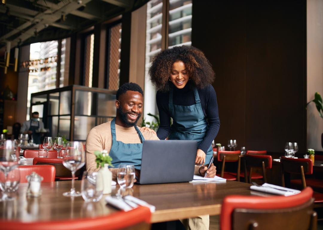 Two business owners in restaurant looking at computer.