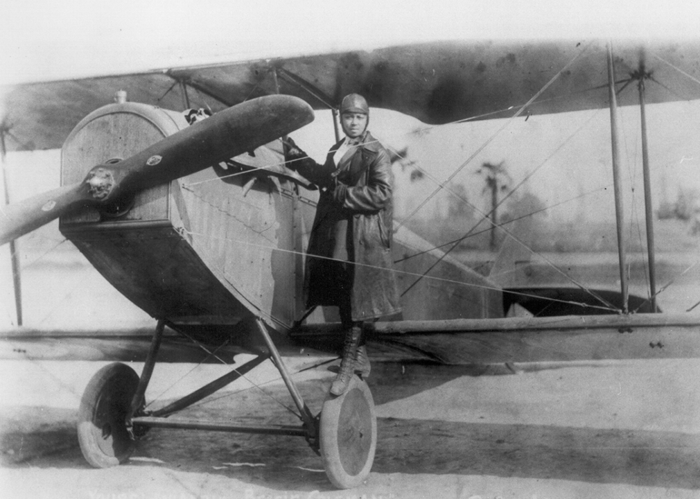 Bessie Coleman poses beside her bi-plane.