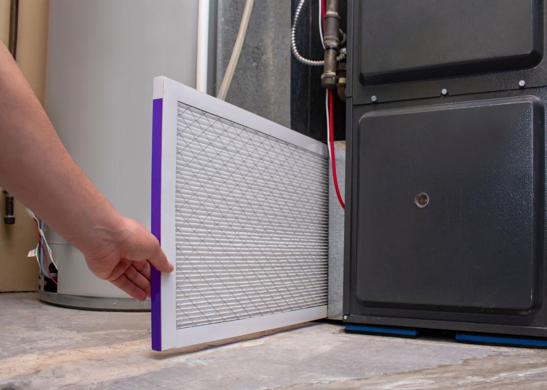 A person changing an air filter on furnace.