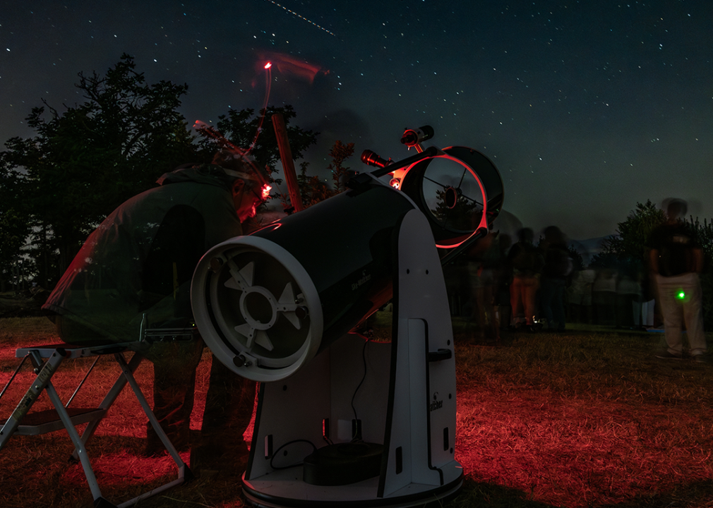 An astronomer is sitting next to his telescope.
