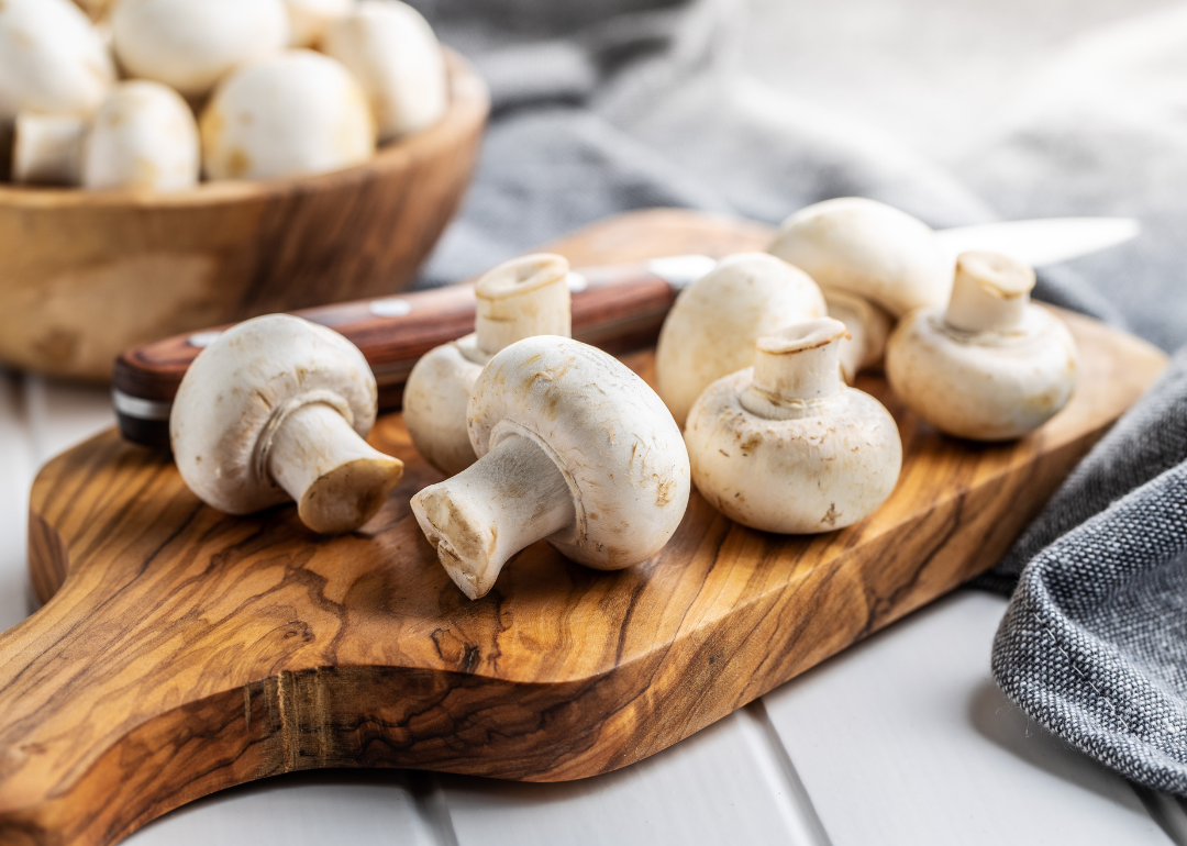 Mushrooms with knife on cutting board.