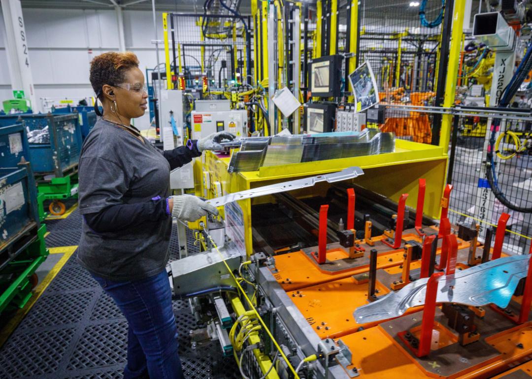 Woman making parts in auto factory.