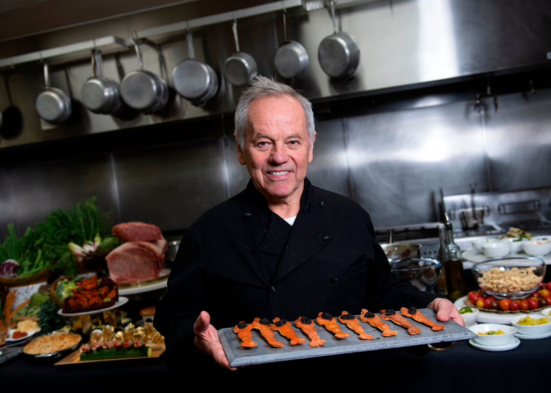 Wolfgang Puck poses in the kitchen with smoked salmon and caviar Oscar statues.