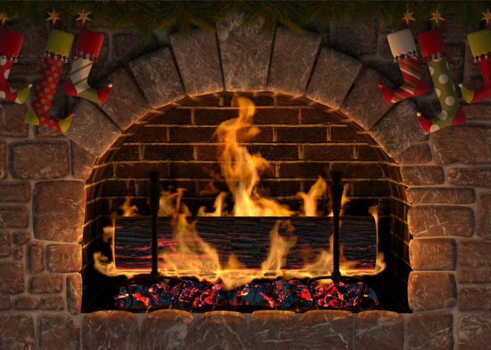 A realistic digital illustration of a lit yule log in a fireplace with stockings hanging from the mantle.