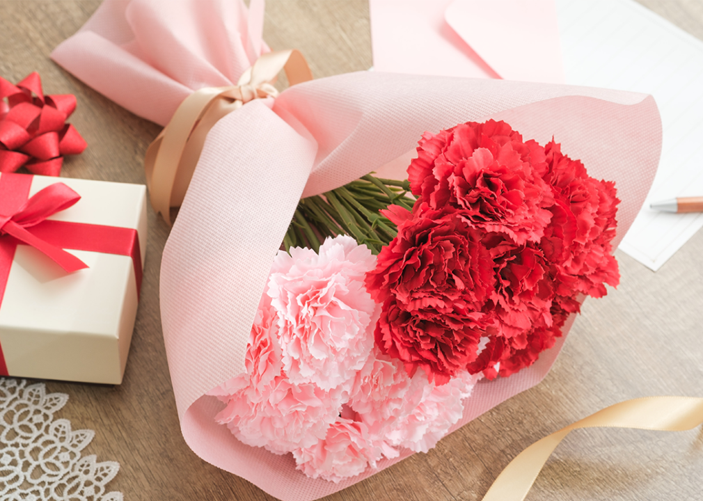 Red Mother’s day carnation bouquet and gift on table.