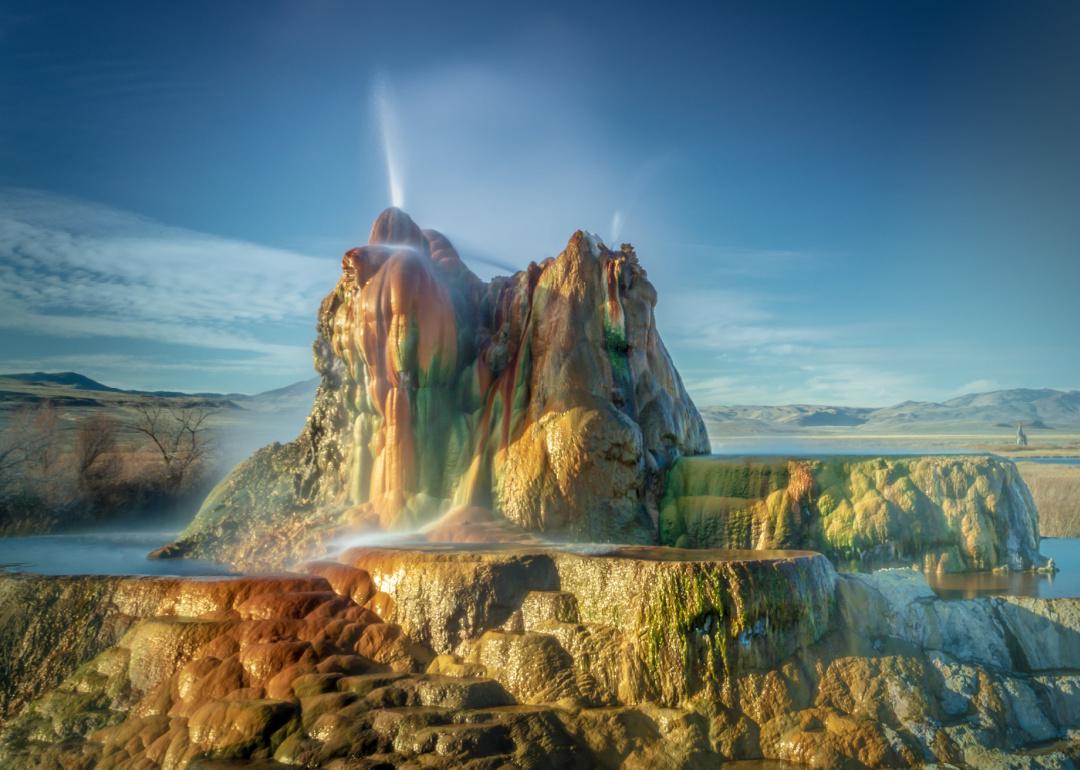 Water spouting from Fly Geyser on a sunny day.