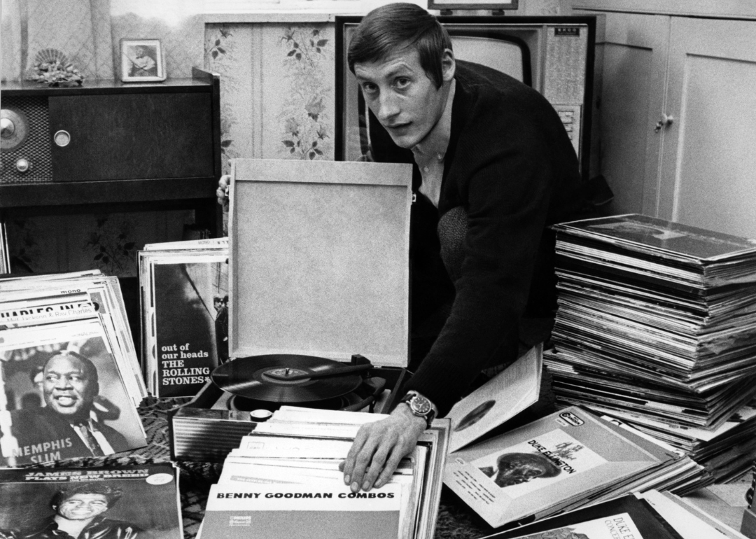 Man displaying jazz record collection at home.