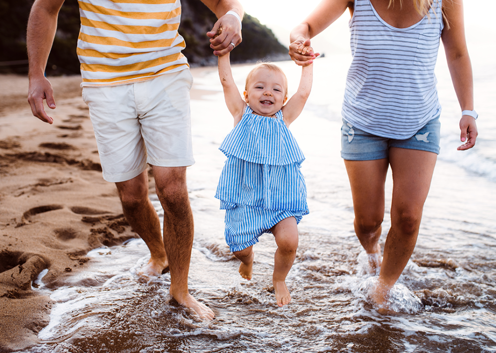 Parents with toddlerwalking on beach.