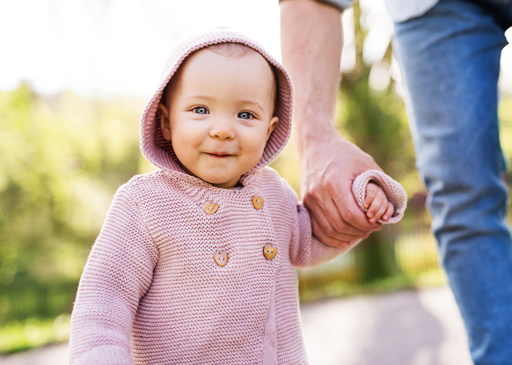 Father holding daughter’s hand outside.