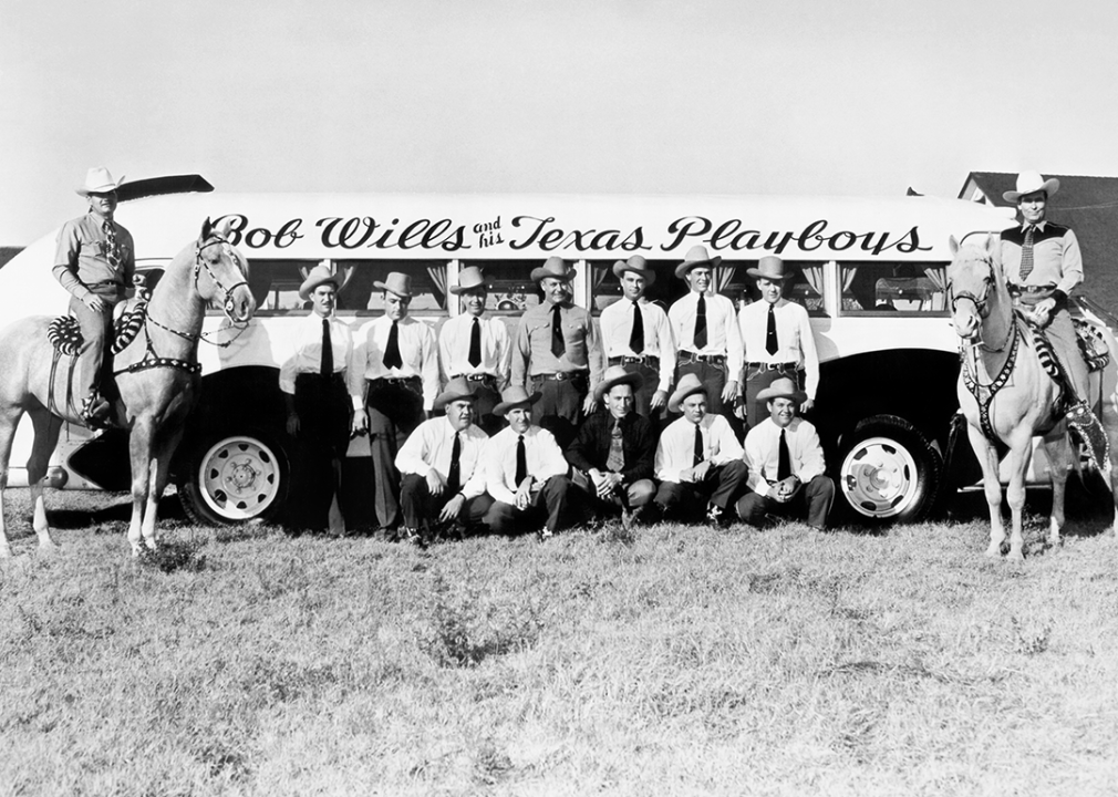 Bob Wills and His Texas Playboys pose with horses and tour bus.
