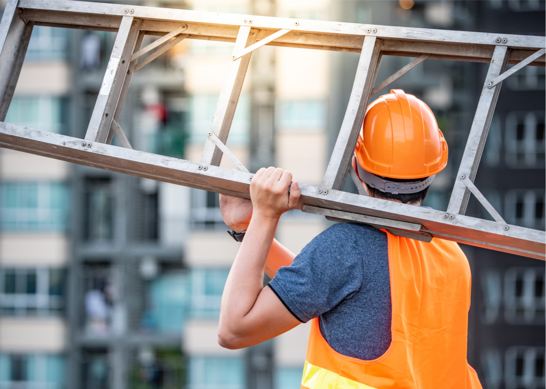 Construction worker carrying ladder