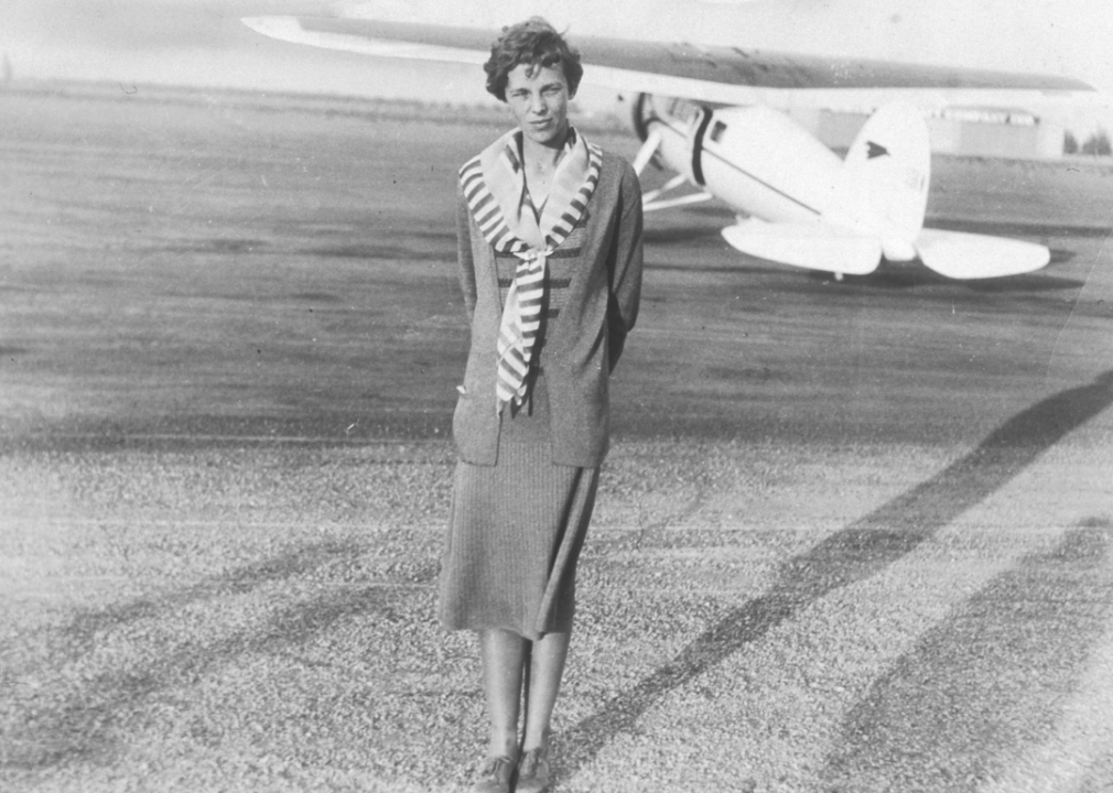 Amelia Earhart stands beside plane
