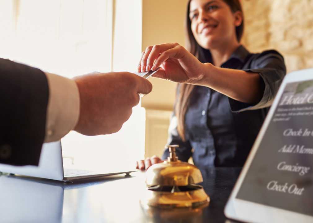 Guest takes room key card at hotel reception desk