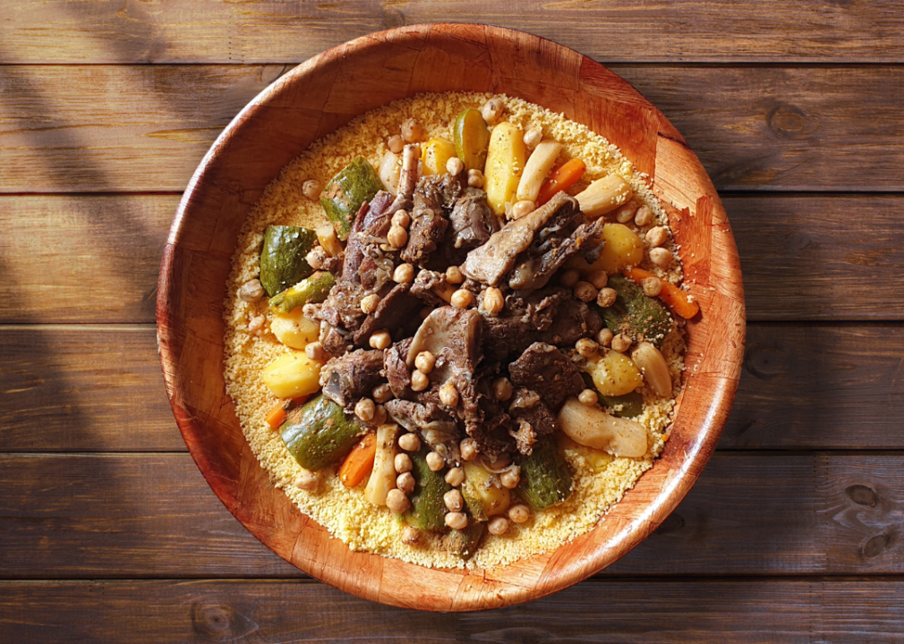 Bowl with meat, vegetables, and couscous on table