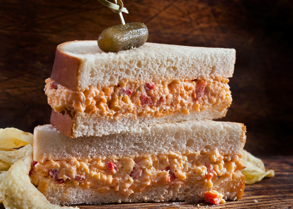 Sliced pimento cheese sandwich halves and stacked on a wooden table.