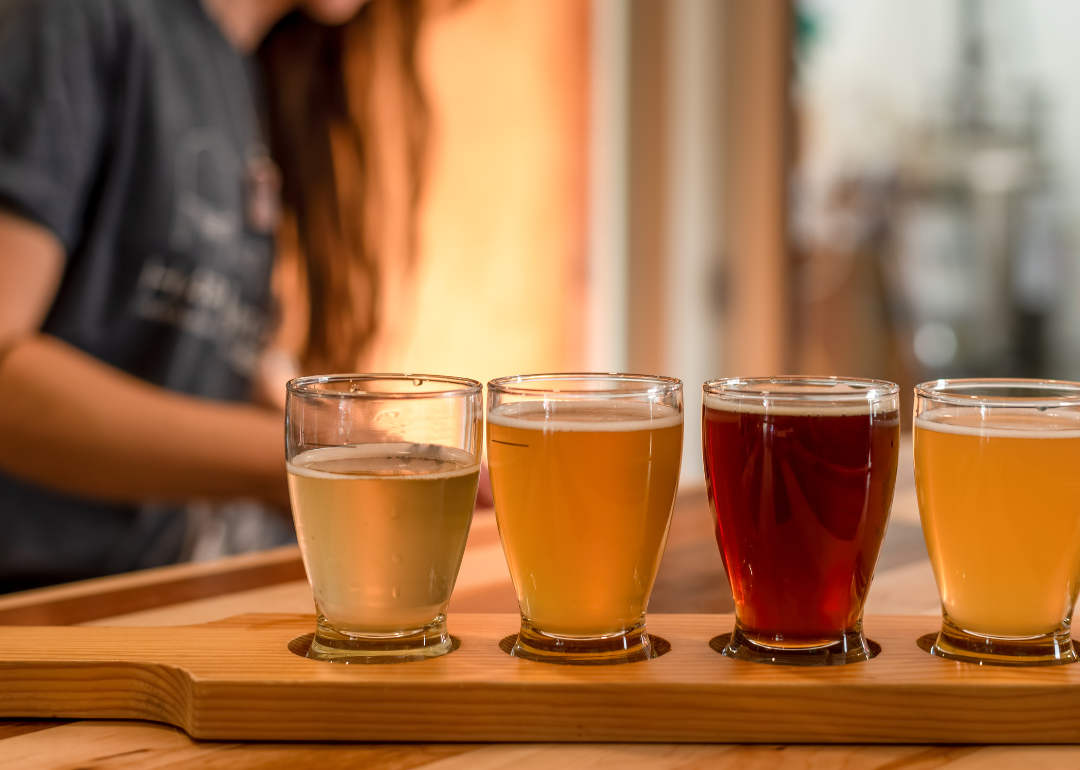 Person standing behind a flight of specialty beers.