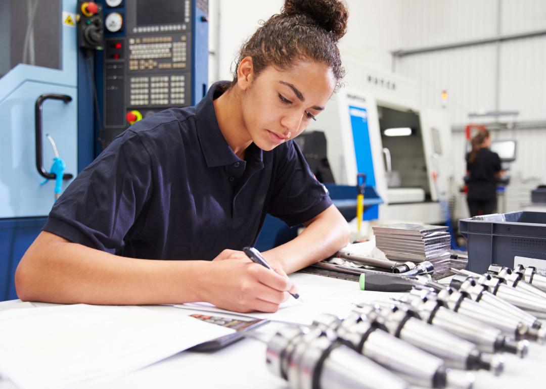 Engineer planning project with machinery in background.