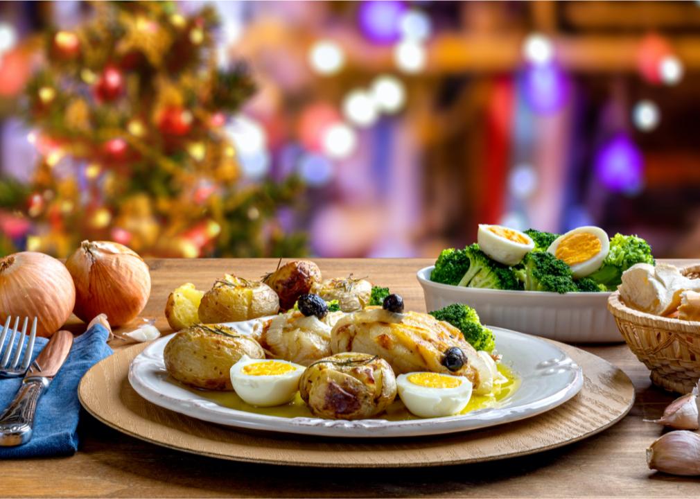 A plate on a table with potatoes, boiled eggs, fish and broccoli. 