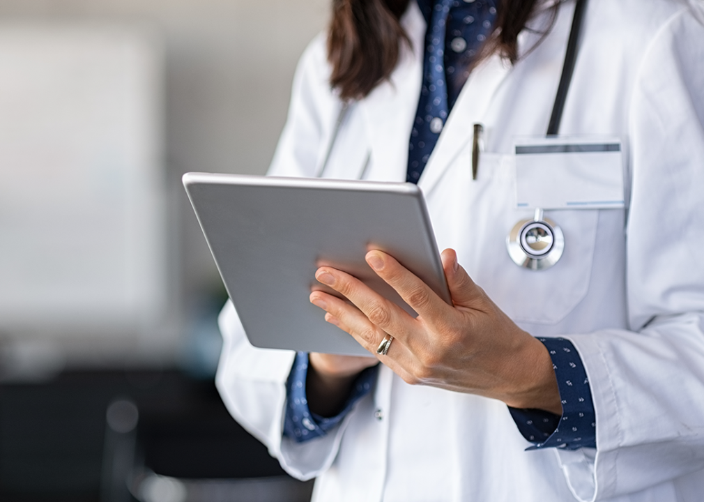 Cropped view of medical professional holding tablet.