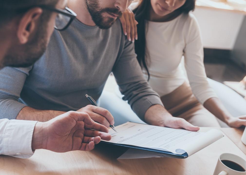 Photo shows a closeup of three people reviewing an official document on a clipboard