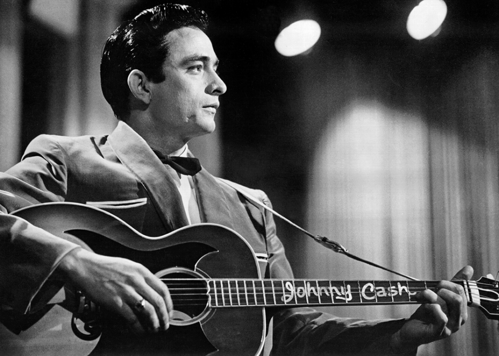 Johnny Cash performs onstage with an acoustic guitar.