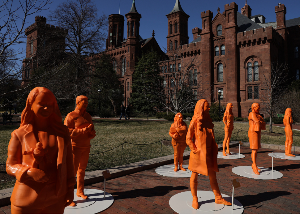 A photo of seven life-size 3D-printed statues honoring women in STEM at the Enid A. Haupt Garden outside the Smithsonian Castle at night 
