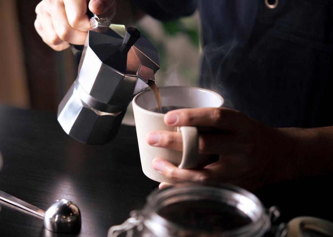 Barista pouring coffee from mocha pot.