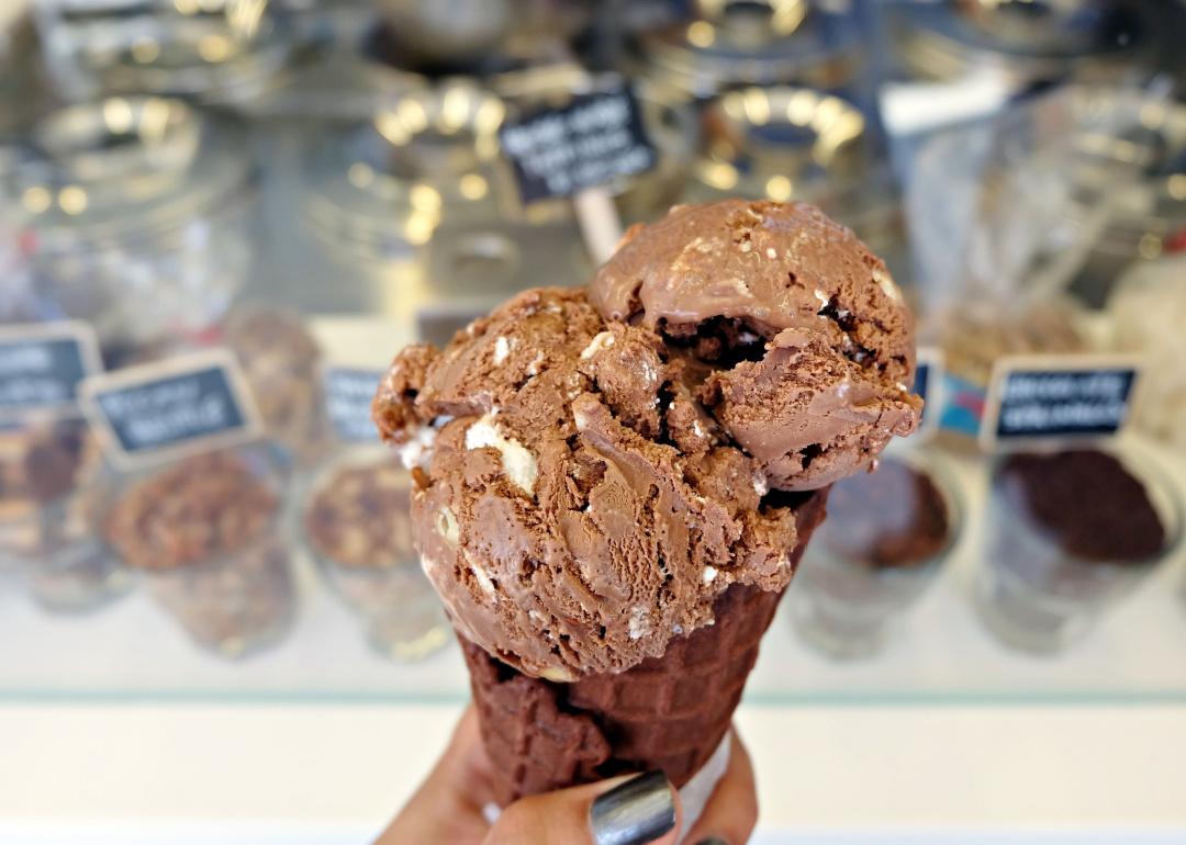 Hand holding waffle cone with rocky road ice cream.
