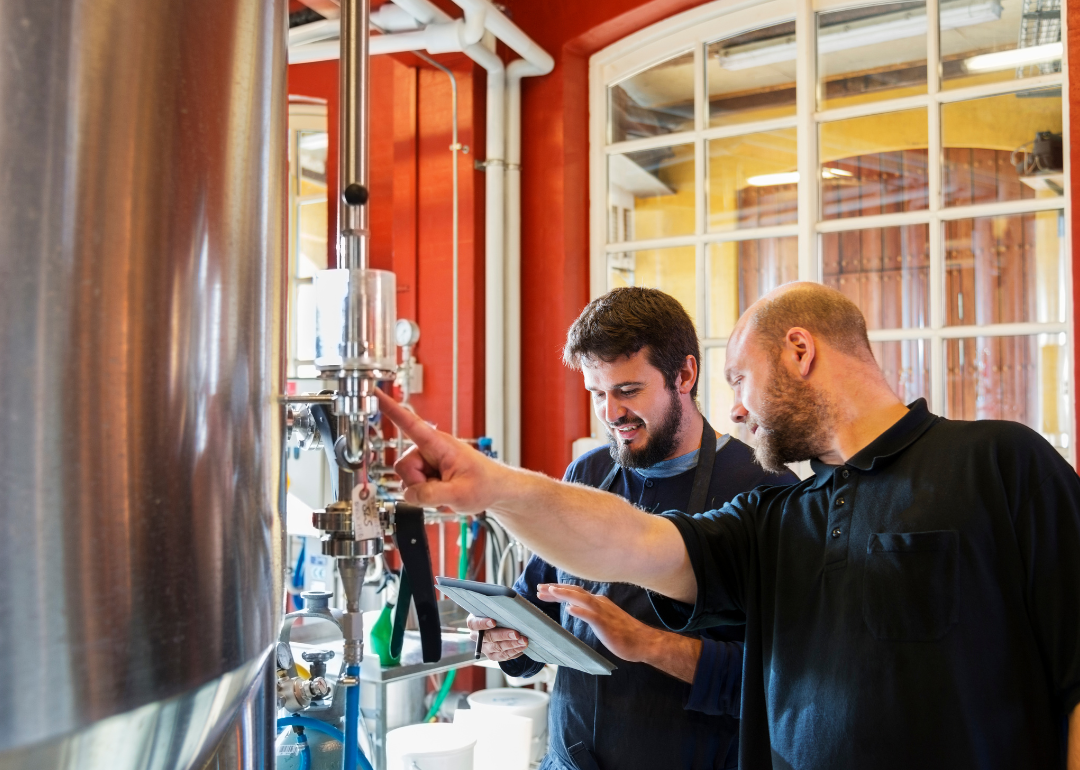#19. West Virginia Two people work a brewing machine, with one holding a tablet.