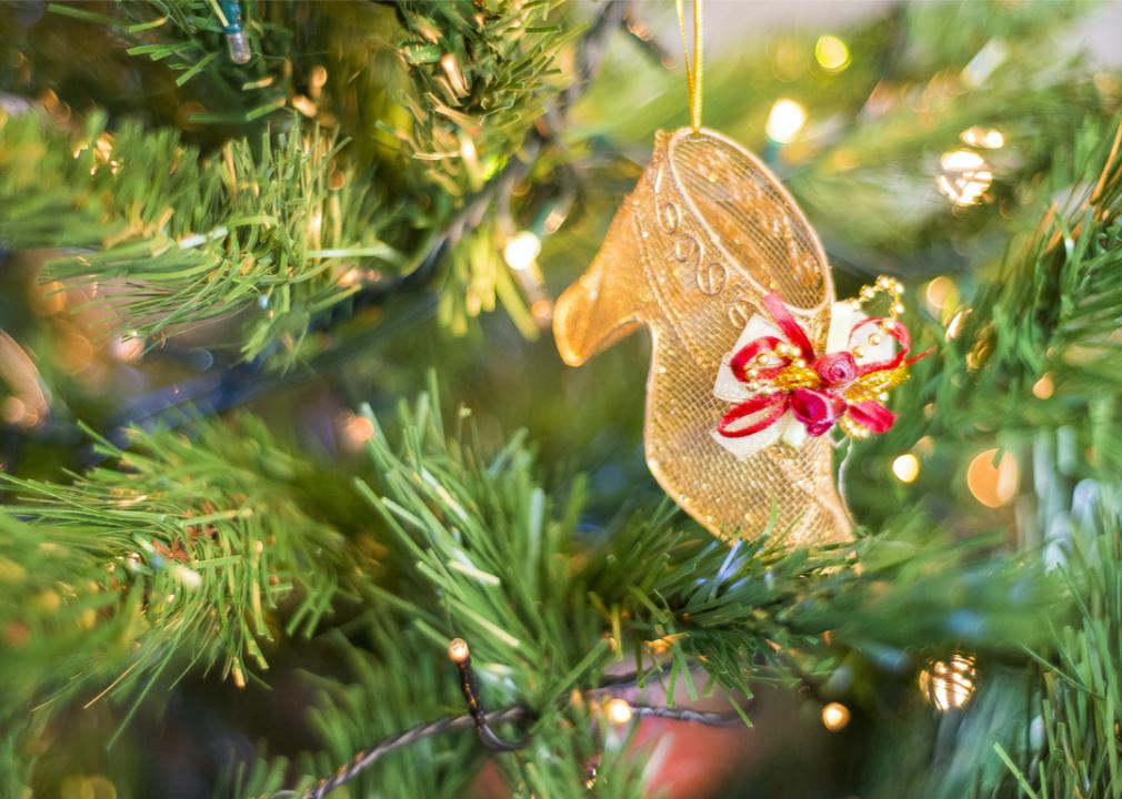 A gold shoe ornament on a lit Christmas tree.