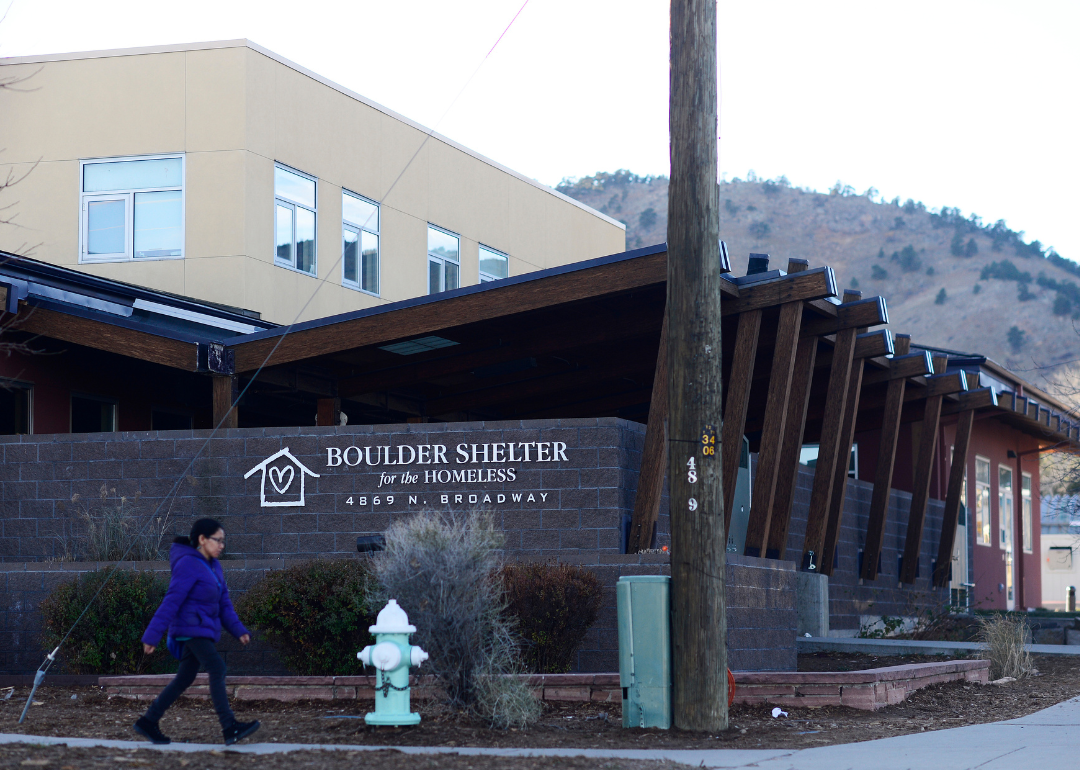 A woman walks past the front of the Boulder Shelter for the Homeless building