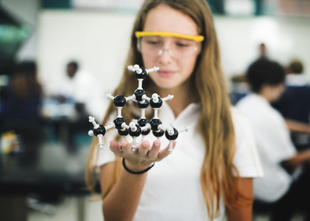 High school student holding molecule structure in chemistry class.