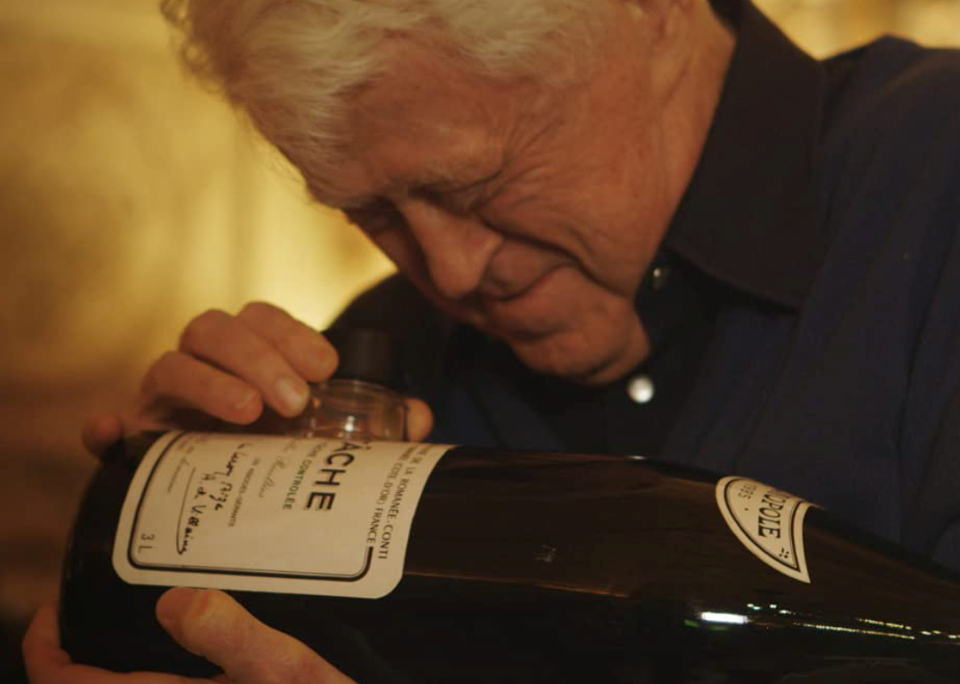 Man inspecting wine bottle in a scene from ‘Sour Grapes.'