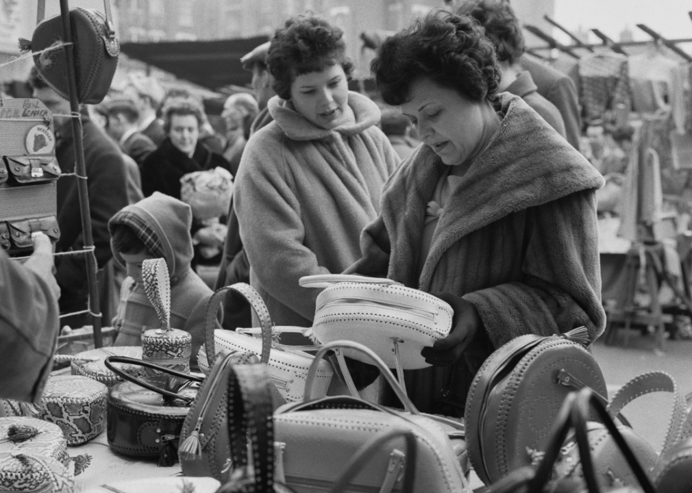 Two women handbag shopping in street market.