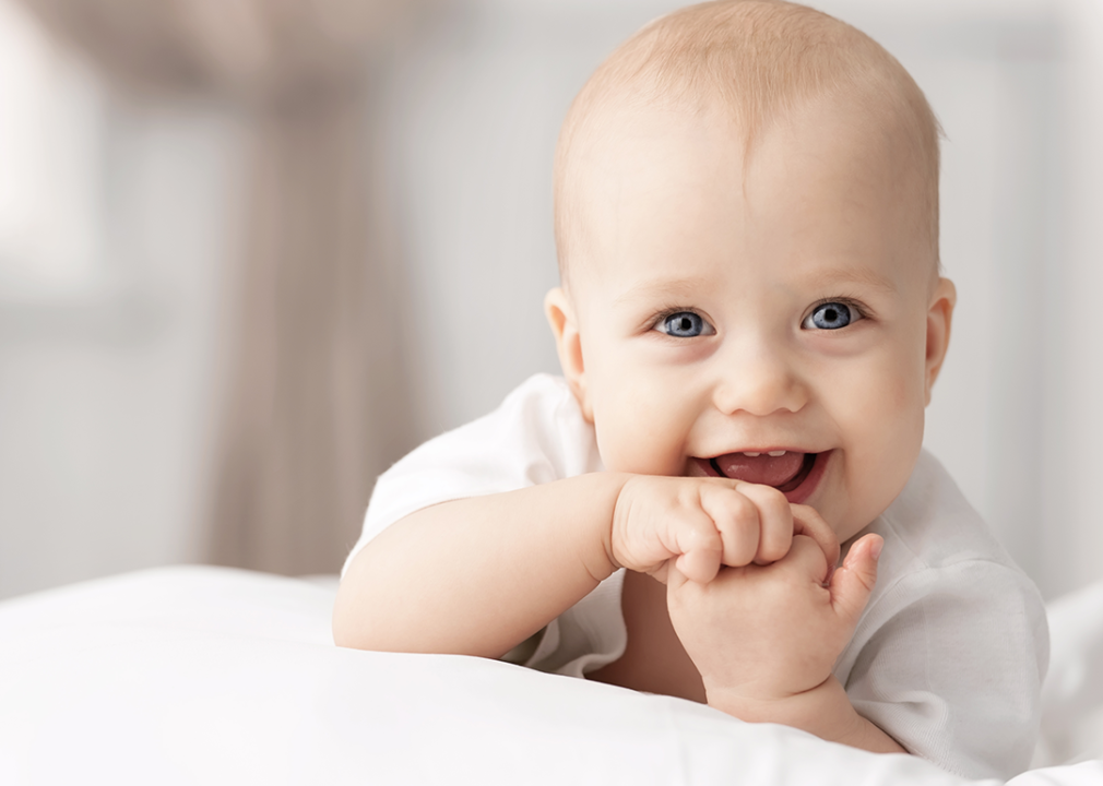 Baby with big smile laying on tummy.