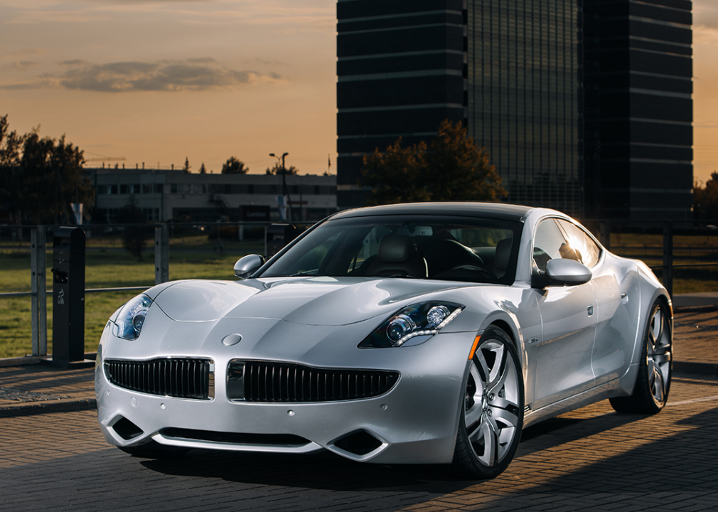 Silver Fisker Karma EVER parked by buildings.