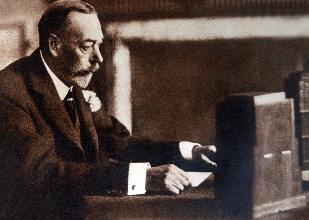 King George V sits at a table making radio address.