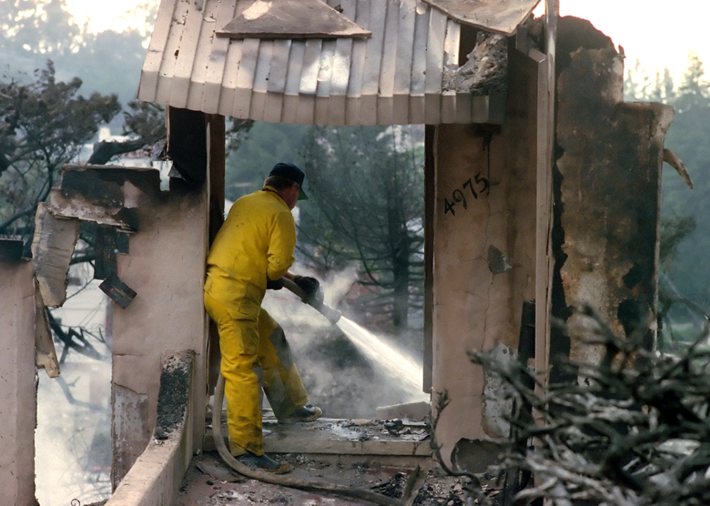 A firefighter with the Tuolumne County Fire Department fights hot spots in a destroyed house.